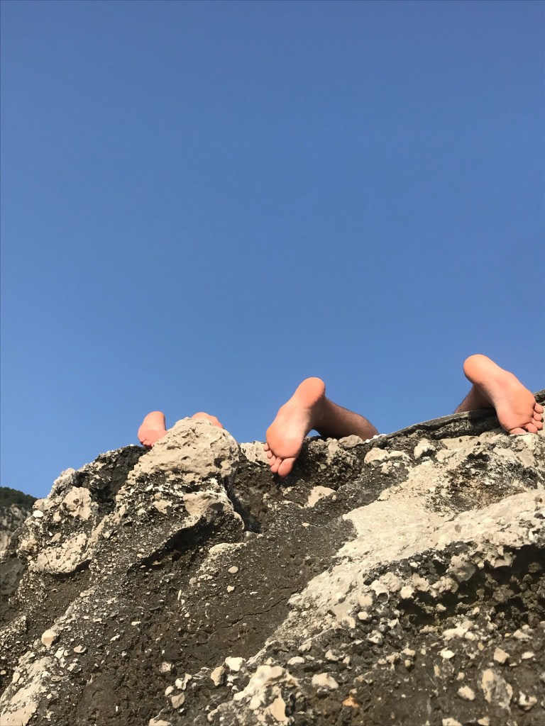 photograph of people by the beach with only feet visible